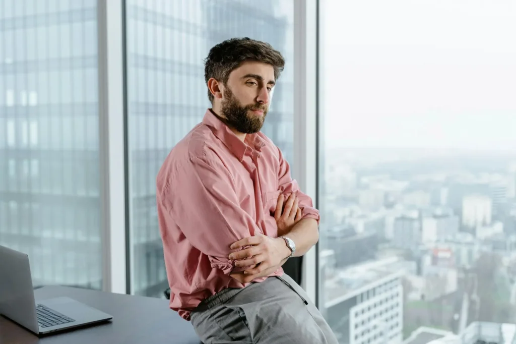 Man sitting on a desk looking out the window.