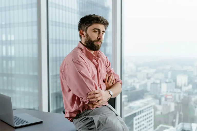 Man sitting on a desk looking out the window.
