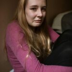 Young woman sitting on the floor with a distressed expression, symbolizing emotional pain and the impact of childhood trauma.