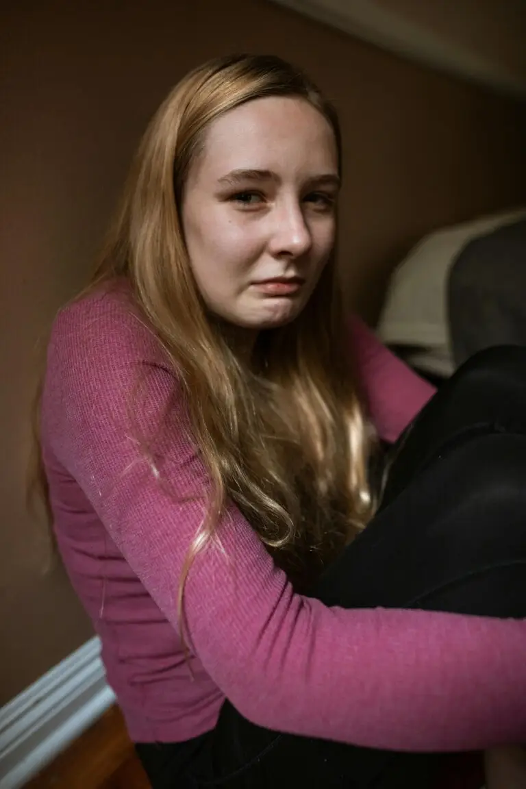 Young woman sitting on the floor with a distressed expression, symbolizing emotional pain and the impact of childhood trauma.