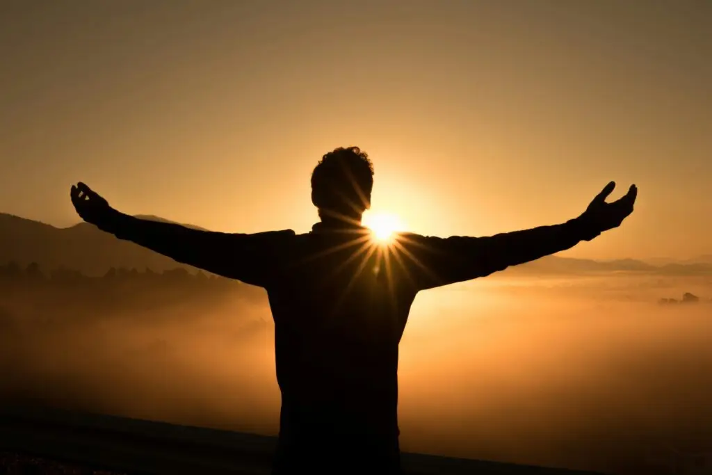Person standing with open arms at sunrise symbolizing hope, calm, and relief from anxiety after EMDR and neurofeedback therapy in Conroe, Montgomery & The Woodlands Texas.
