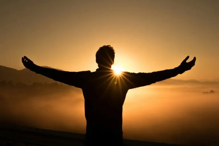Person standing with open arms at sunrise symbolizing hope, calm, and relief from anxiety after EMDR and neurofeedback therapy in Conroe, Montgomery & The Woodlands Texas.