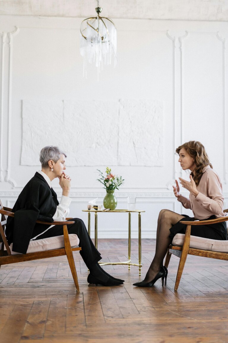 Therapist and client seated face-to-face in a calm counseling office, engaged in a focused mental health therapy session.