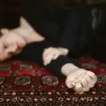 Person lying on a patterned rug holding a ring, illustrating emotional withdrawal and loneliness during depression
