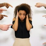 Woman experiencing social anxiety while surrounded by pointing hands, representing fear of judgment and emotional overwhelm often addressed in social anxiety therapy in Conroe, TX