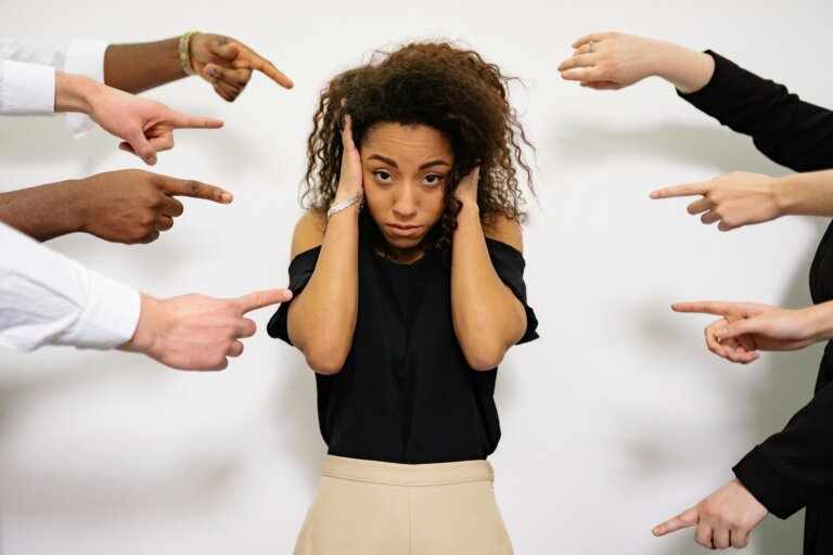 Woman experiencing social anxiety while surrounded by pointing hands, representing fear of judgment and emotional overwhelm often addressed in social anxiety therapy in Conroe, TX