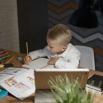 Young child calmly working on homework at a desk representing improved focus and emotional regulation through microcurrent neurofeedback therapy