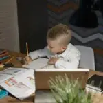 Young child calmly working on homework at a desk representing improved focus and emotional regulation through microcurrent neurofeedback therapy