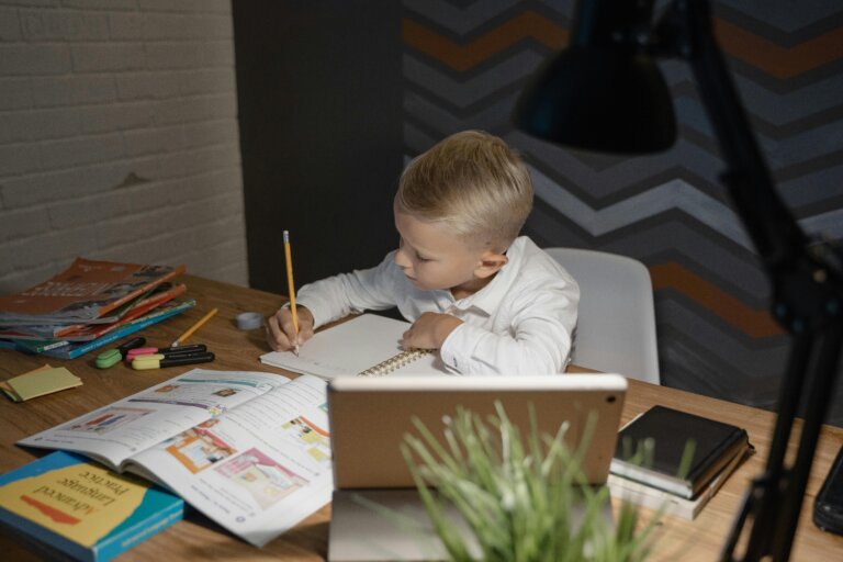 Young child calmly working on homework at a desk representing improved focus and emotional regulation through microcurrent neurofeedback therapy