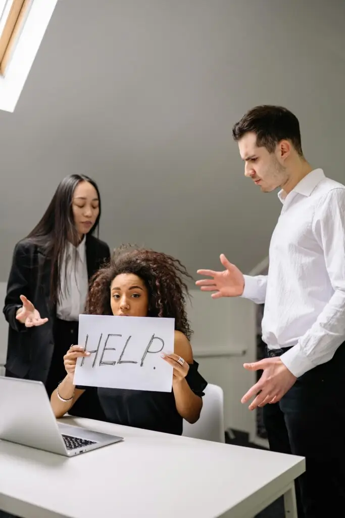 Threat-focused brain and workplace anxiety as a woman holds a help sign while feeling overwhelmed by stress