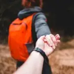 Person holding hands while walking through woods symbolizing trust, emotional support, and the therapeutic healing journey.