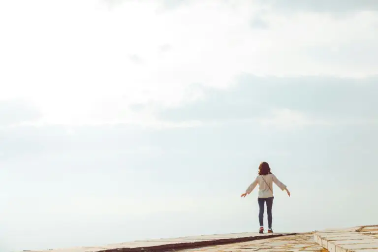 Woman standing with arms open on a path symbolizing freedom with radical responsibility and emotional resilience