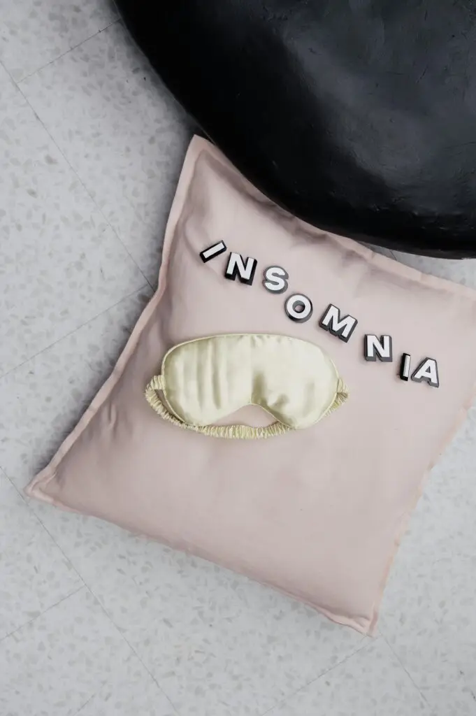 Person struggling with insomnia represented by sleep mask and “insomnia” text, symbolizing trauma-related sleep disruption