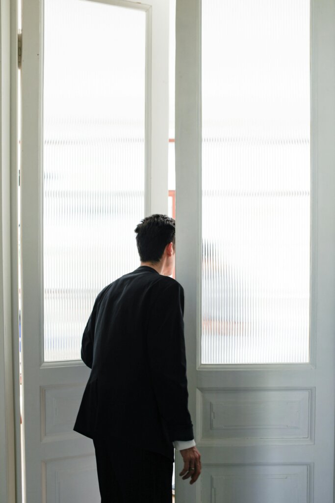 Person standing in front of bright frosted windows, symbolizing emotional overwhelm, anxiety, and emotional contagion.