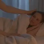 Child resting in bed with parent support while exploring neurofeedback therapy for sleep problems and bedwetting in Conroe TX