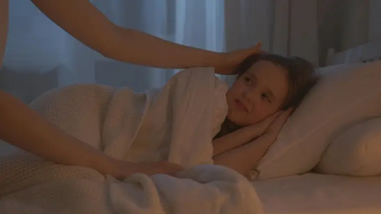 Child resting in bed with parent support while exploring neurofeedback therapy for sleep problems and bedwetting in Conroe TX