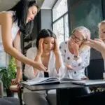 Woman feeling mentally overwhelmed during a workplace discussion, illustrating executive functioning and attention challenges that many women with ADHD experience.