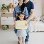 Adoptive parents standing with their young daughter after adoption, representing healing, attachment, and trauma-informed family support.