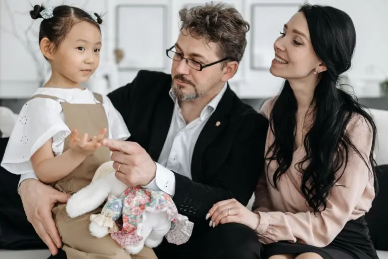 Adoptive parents interacting with their young daughter, illustrating secure attachment, emotional connection, and trauma-informed support for adopted children.