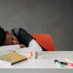 Child resting on a desk while studying, representing ADHD-related mental fatigue, attention challenges, and executive functioning difficulties.