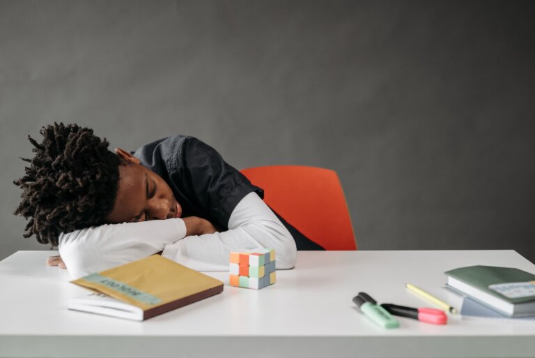 Child resting on a desk while studying, representing ADHD-related mental fatigue, attention challenges, and executive functioning difficulties.